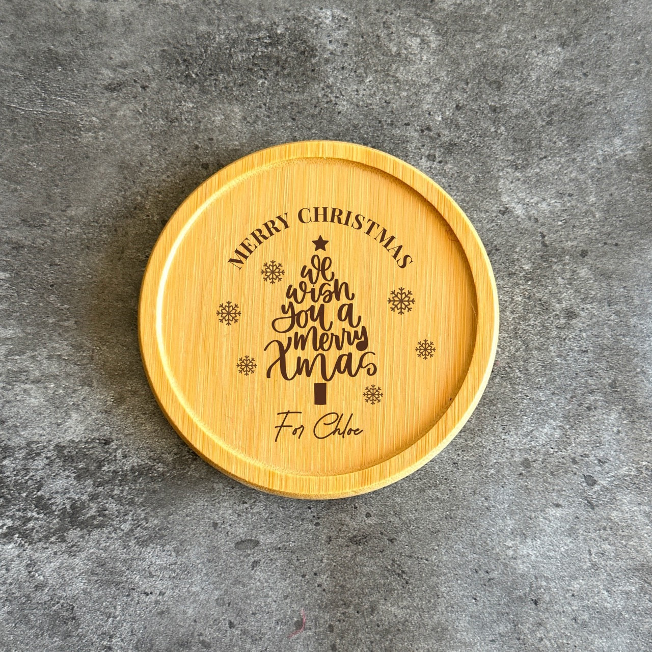 Engraved bamboo coaster reading We Wish You a Merry Xmas