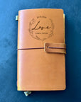 Leather diary with custom cover beside anniversary bouquet