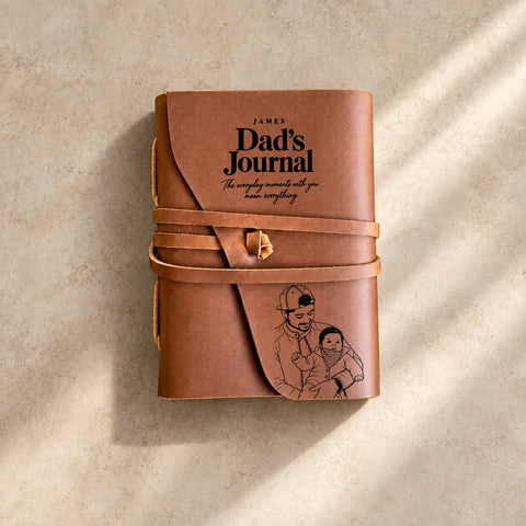 Leather wrap journal tied with a leather cord, engraved with James’s name, Dad’s Journal lettering and a father holding his baby.
