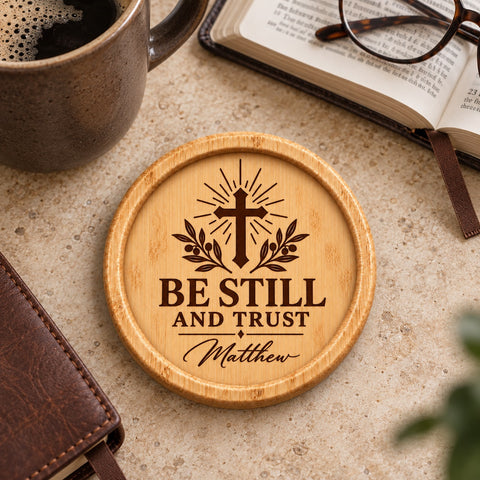 Personalised wooden coaster with a radiant cross, olive branches and Be still and trust wording.