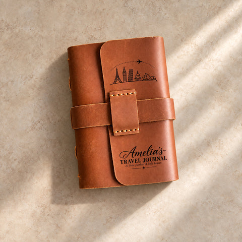 Leather travel journal with strap closure, engraved globe, aeroplane and personalised name.