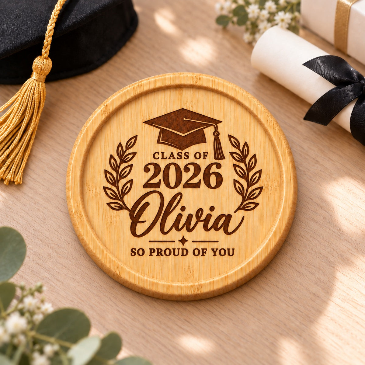 Personalised bamboo graduation coaster engraved with a name, graduation year, mortarboard cap and laurel branches